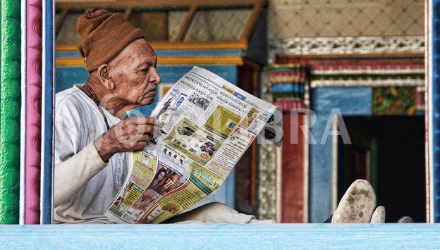 Old Indian man reading a newspaper