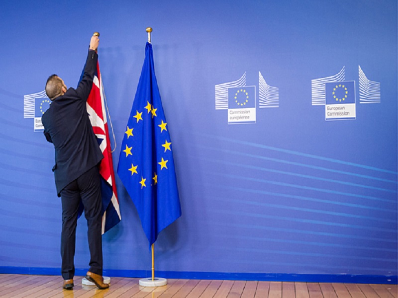 An EU official hangs the Union Jack next to the European Union flag at the VIP entrance at the European Commission headquarters in Brussels on Tuesday, Feb. 16, 2016. British Prime Minister David Cameron is visiting EU leaders two days ahead of a crucial EU summit.  (AP Photo/Geert Vanden Wijngaert)